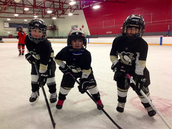 Kids posing with hockey sticks while learning skills